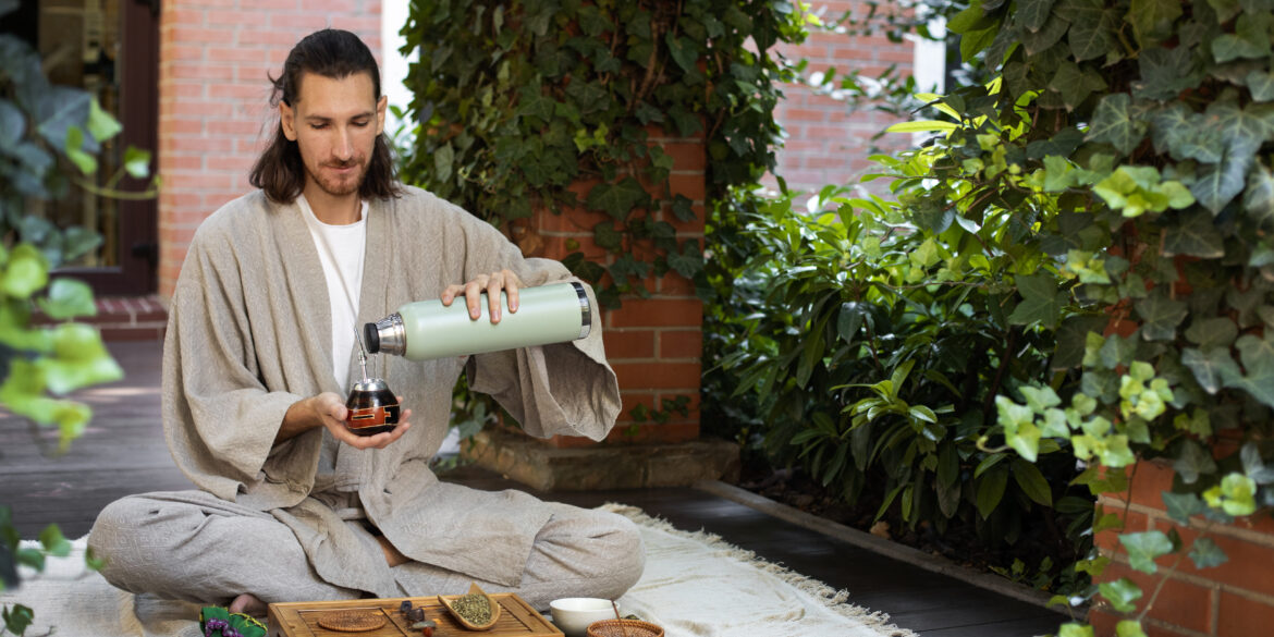 Man pouring ayurvedic tea into a cup from a bottle