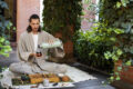 Man pouring ayurvedic tea into a cup from a bottle