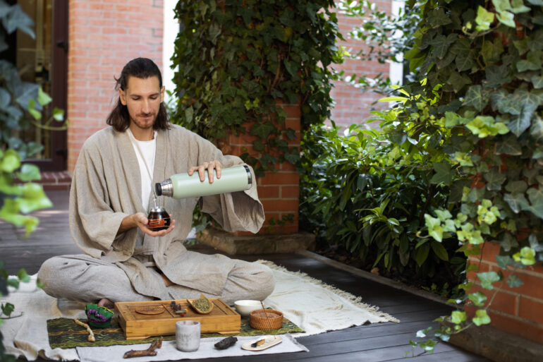 Man pouring ayurvedic tea into a cup from a bottle