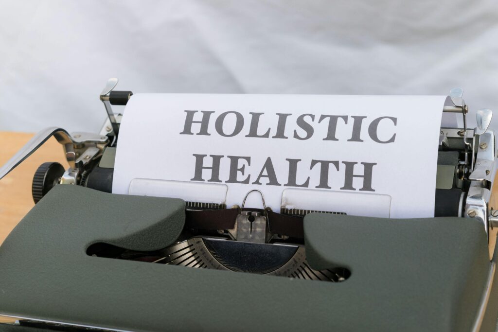 A paper peaking out of a typewriter with HOLISTIC HEALTH written on it