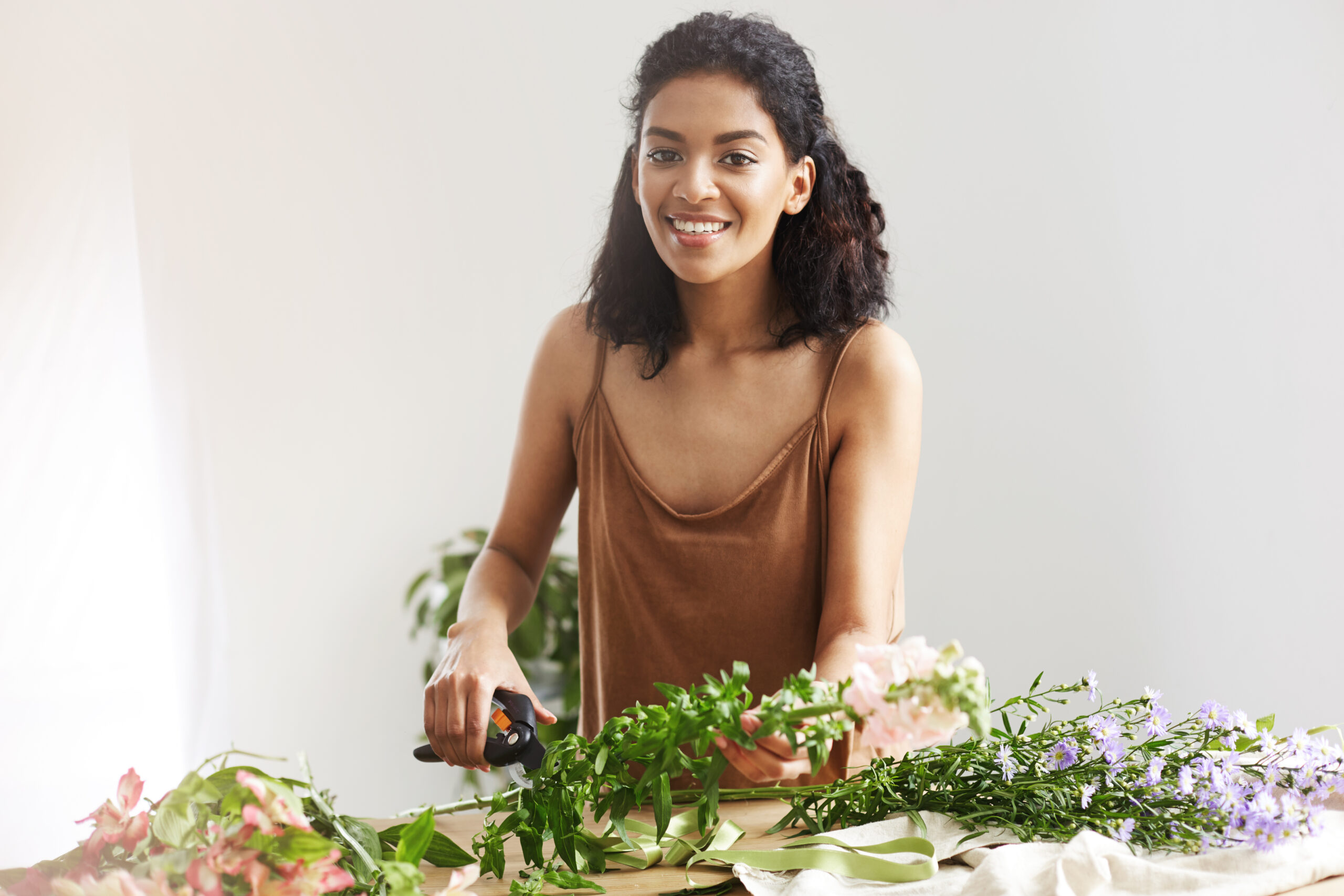african female florist smiling cutting stems working in a flower shop for Hidden Ayurvedic Principles