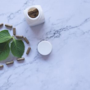 white ayurvedic medicine bottle and herbs