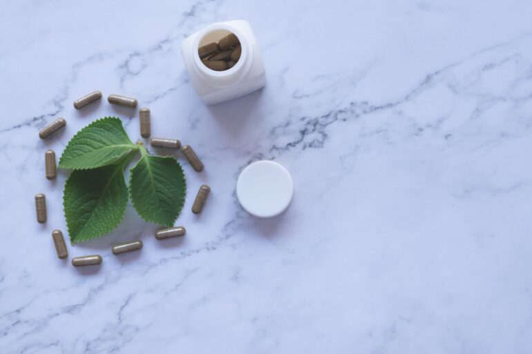 white ayurvedic medicine bottle and herbs