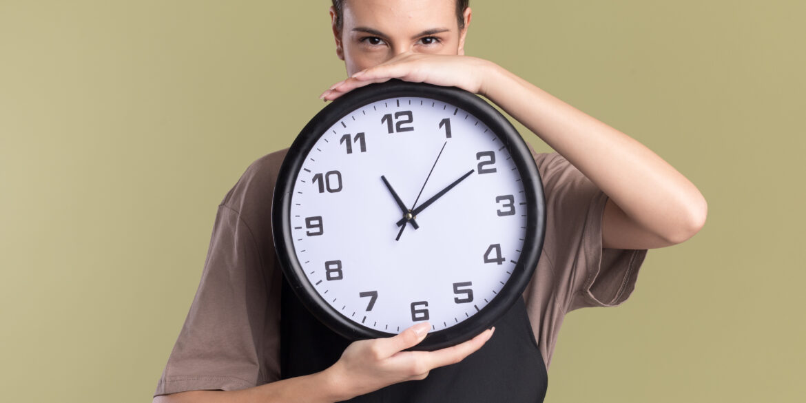 pleased-young-brunette girl holding a clock