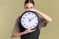 pleased-young-brunette girl holding a clock