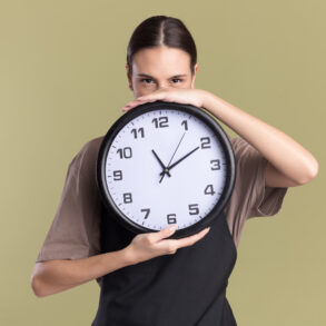 pleased-young-brunette girl holding a clock