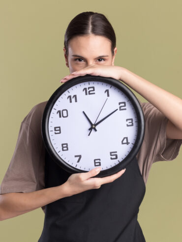 pleased-young-brunette girl holding a clock