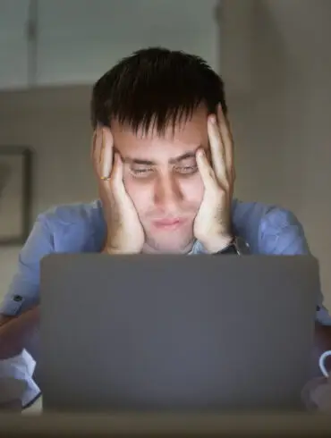 man on a desk near laptop late at night