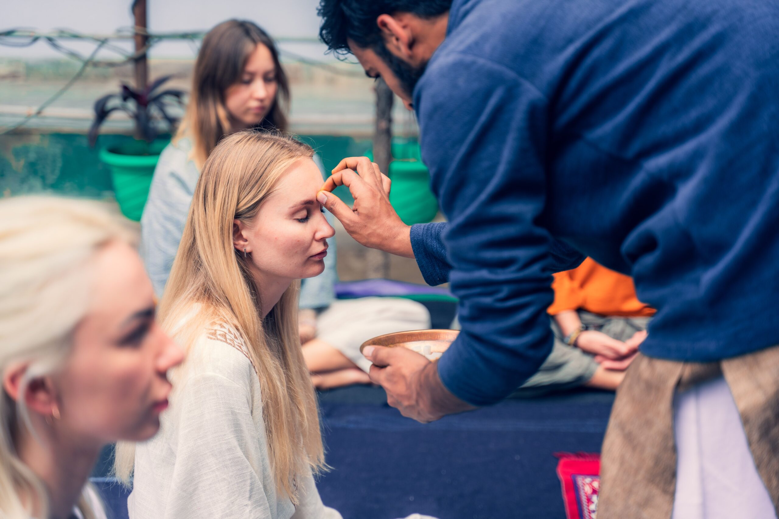 a girl getting a tika on her forehead from a yoga guru for Ayurvedic Self-Healing