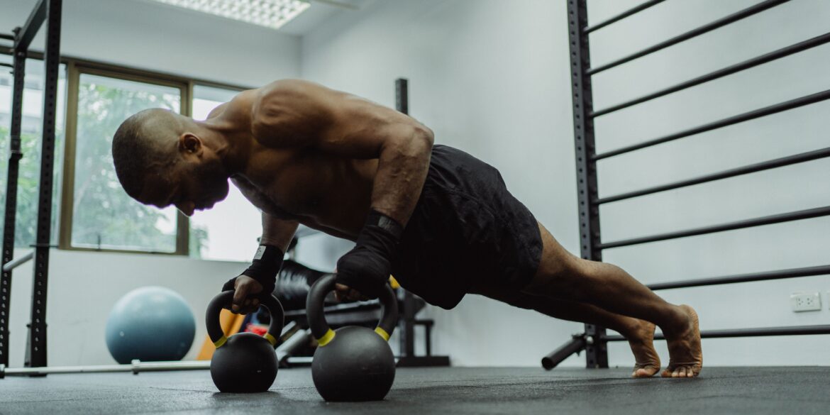 man doing push-ups with a dumble in a gym