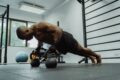 man doing push-ups with a dumble in a gym