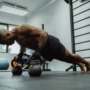 man doing push-ups with a dumble in a gym