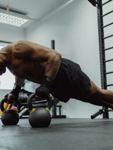 man doing push-ups with a dumble in a gym