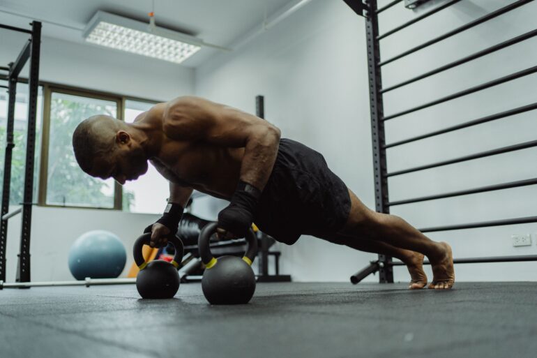 man doing push-ups with a dumble in a gym