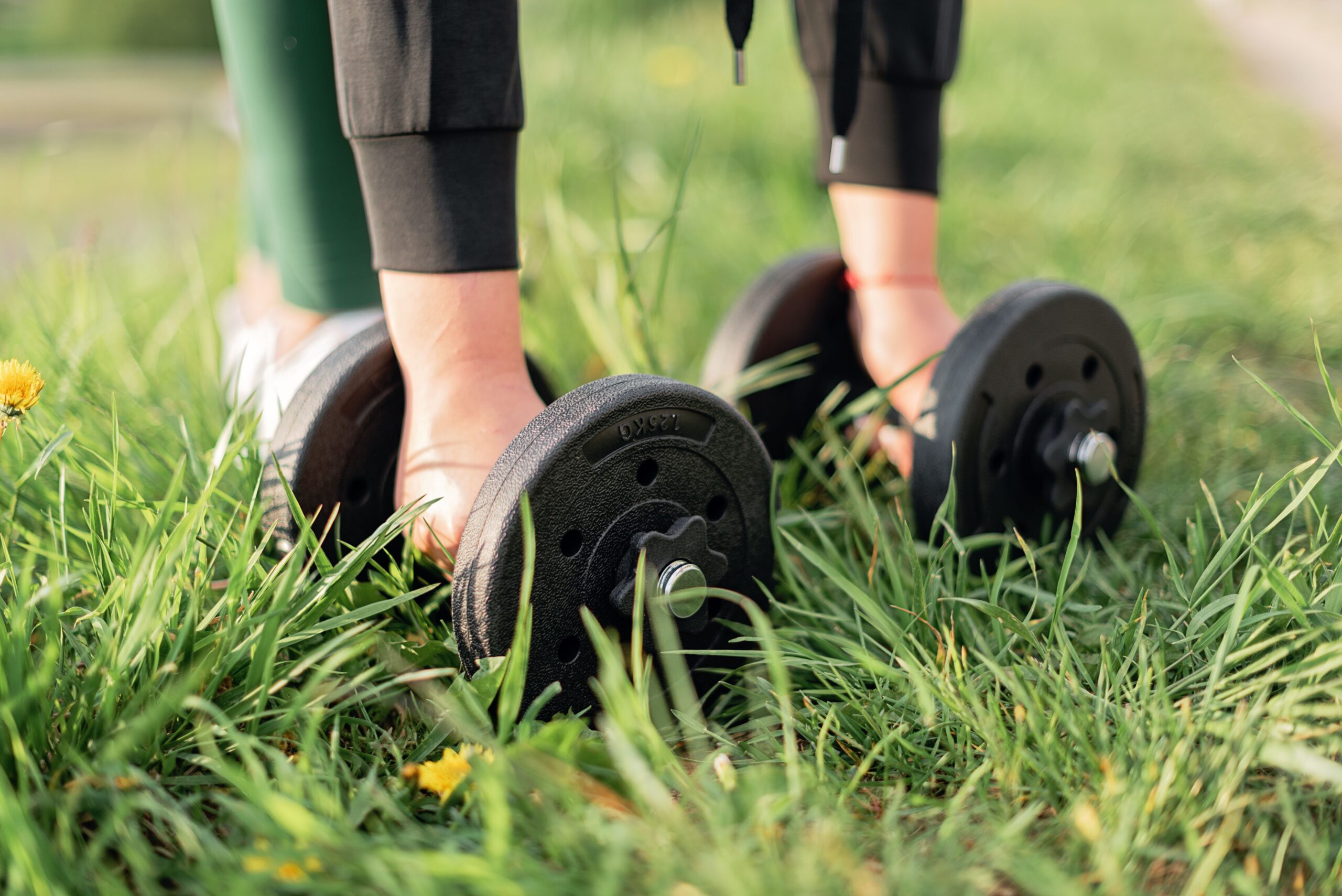 a girl lifting a dumbbell from grass for Ayurvedic Strength Training