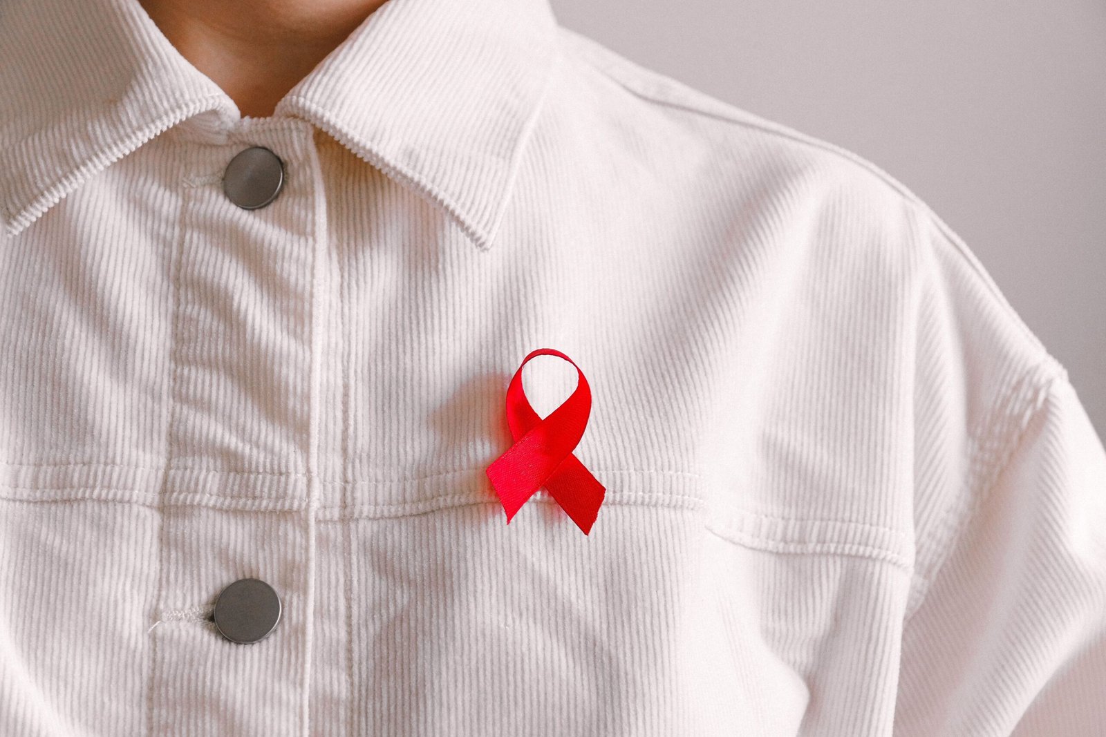 a man wearing a white shirt w2ith a red ribbon because of Over 7,000 diagnosed with HIV in Karnataka