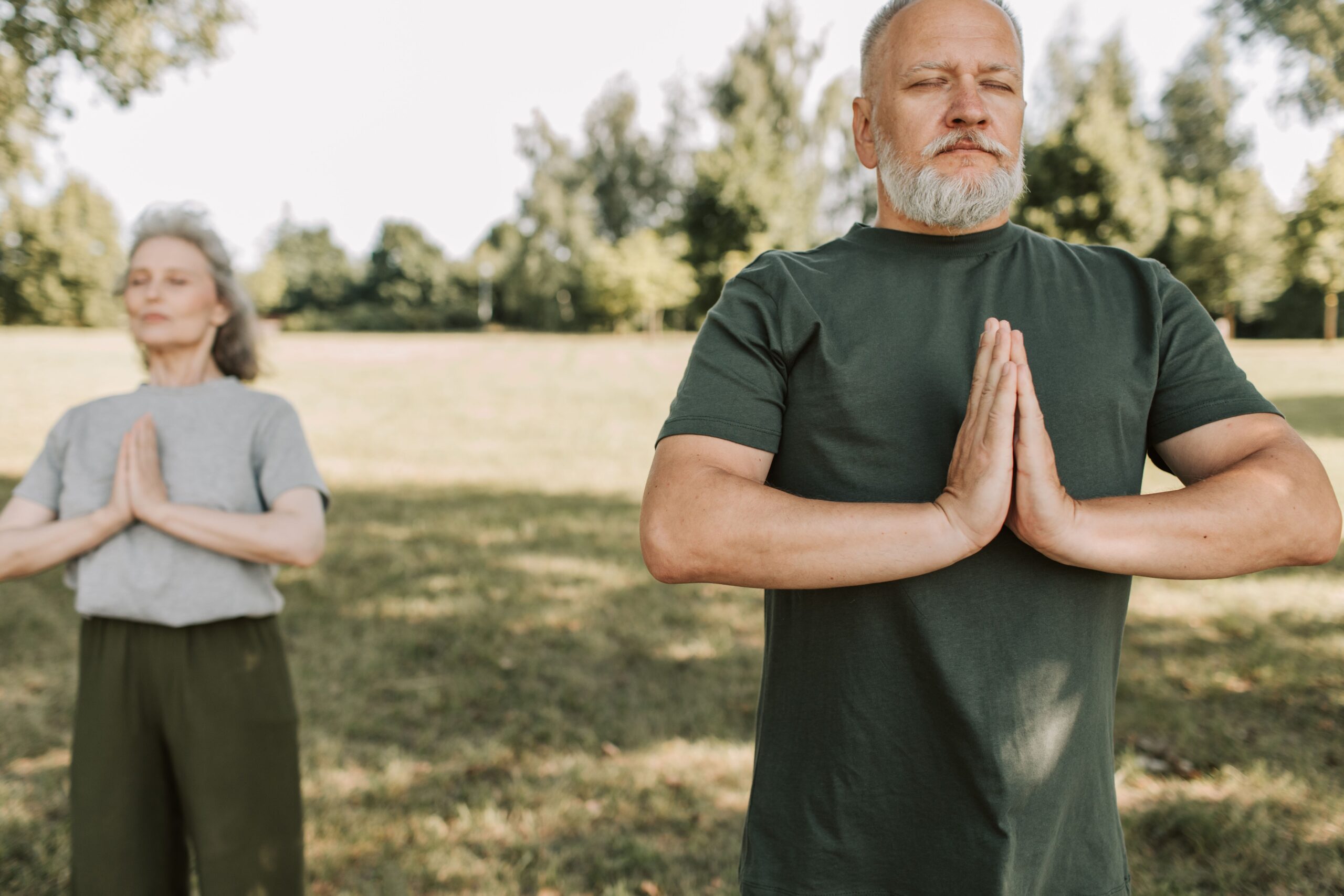 a man and a woman doing a yoga pose in a park for Ayurveda for Healthy Aging