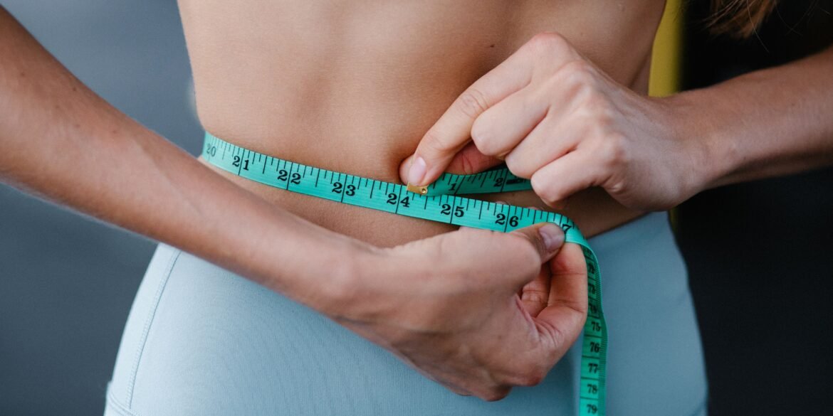 a woman measuring her waist with an inch tape