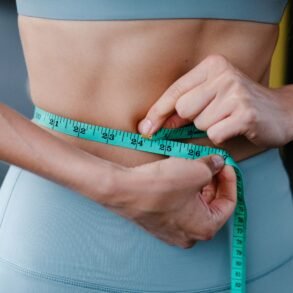 a woman measuring her waist with an inch tape