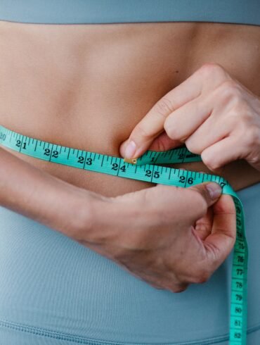 a woman measuring her waist with an inch tape
