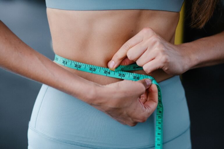 a woman measuring her waist with an inch tape