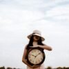 a woman holding a large clock
