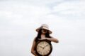 a woman holding a large clock