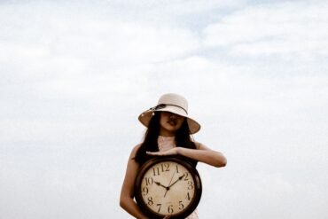 a woman holding a large clock