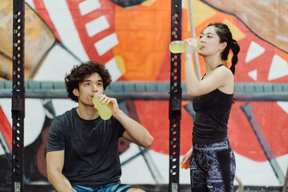 a boy and a girl drinking energy juice from bottles
