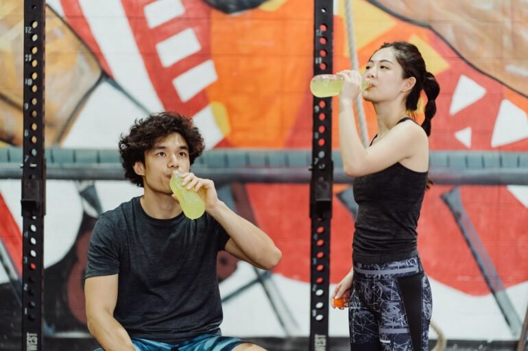 a boy and a girl drinking energy juice from bottles