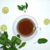 herbal tea in a cup and lime and herbs scattered around it