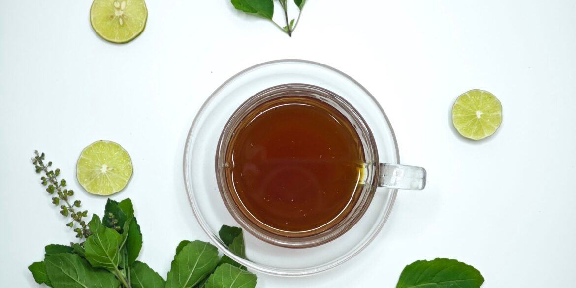 herbal tea in a cup and lime and herbs scattered around it