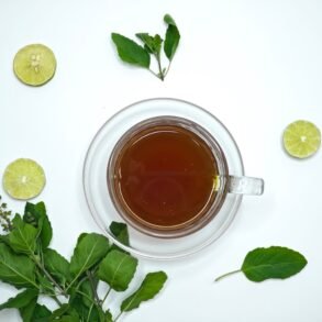 herbal tea in a cup and lime and herbs scattered around it