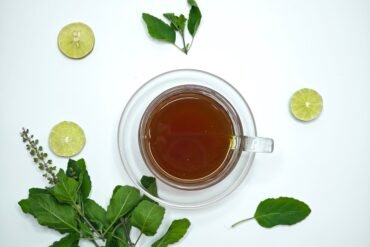 herbal tea in a cup and lime and herbs scattered around it