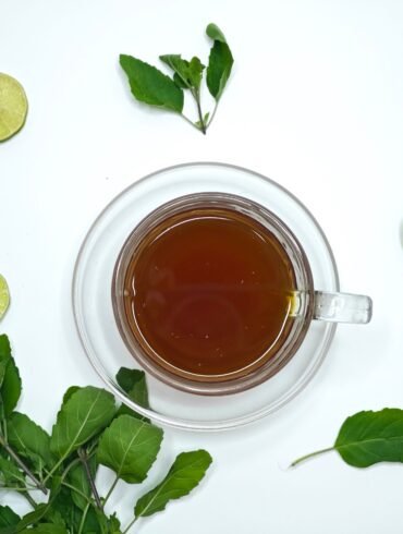 herbal tea in a cup and lime and herbs scattered around it