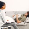a therapist sitting on a chair while her patient sits on the couch