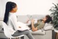 a therapist sitting on a chair while her patient sits on the couch