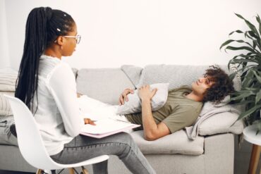 a therapist sitting on a chair while her patient sits on the couch