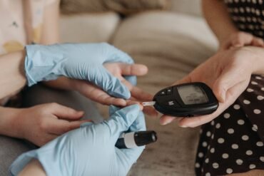 nurse measuring blood sugar of aq girl wearing gloves