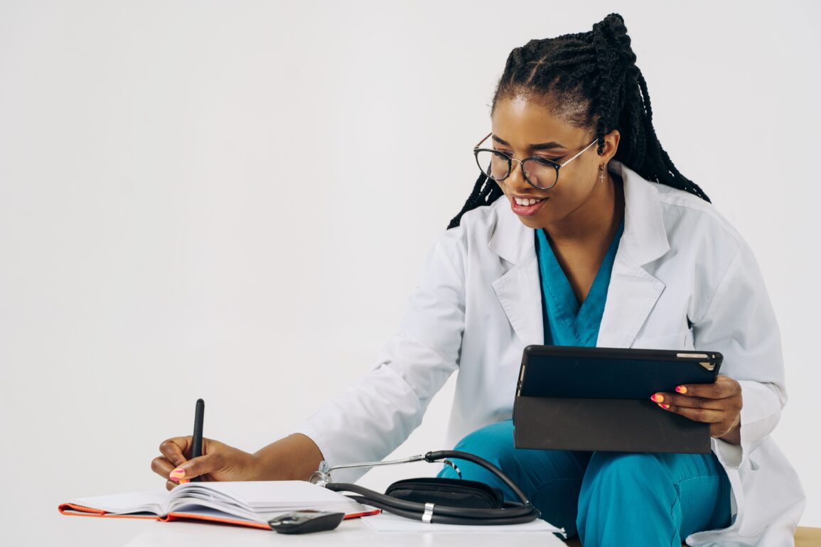 a doctor writing something down on her notebook while holding a device