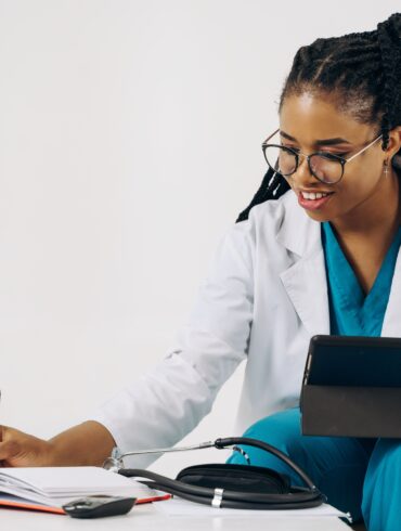 a doctor writing something down on her notebook while holding a device