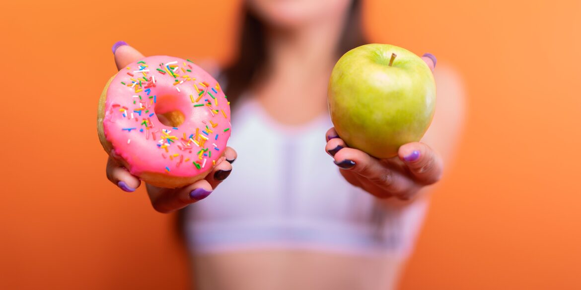 a woman holding a donut and a green apple