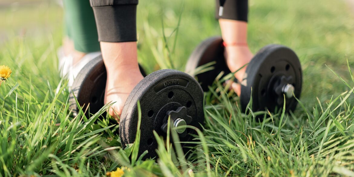 a girl picking up dumbbells in a park for Gym Exercises