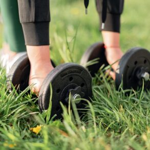 a girl picking up dumbbells in a park for Gym Exercises