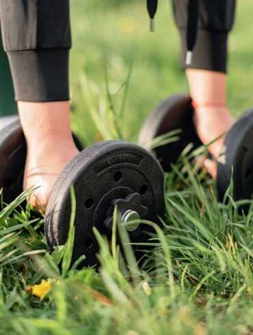 a girl picking up dumbbells in a park for Gym Exercises