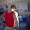 a man flexing his muscles in a bright red vest