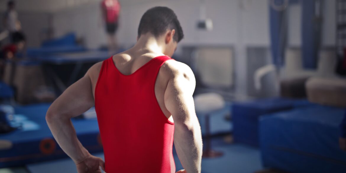 a man flexing his muscles in a bright red vest