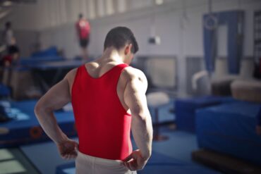 a man flexing his muscles in a bright red vest