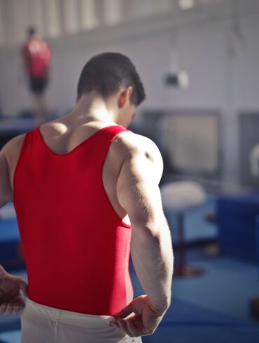 a man flexing his muscles in a bright red vest